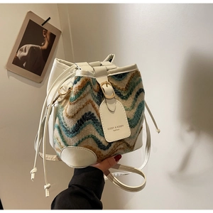 Close-up of zigzag knit bucket bag featuring white leather drawstring and gold hardware