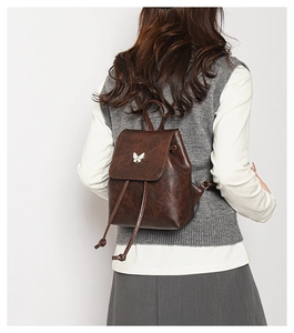 Detail view of vintage brown leather backpack with white butterfly metal buckle decoration