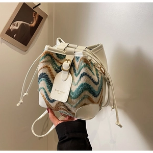 Detail of chevron tweed bucket bag featuring white leather trims and branded hangtag