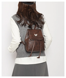 Detail shot of mini brown vintage backpack with silver butterfly hardware on flap
