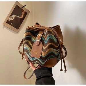 Close-up of retro bucket bag with woven wavy patterns and brown leather trim detailing