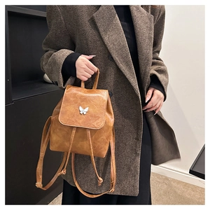 Detail of vintage caramel backpack featuring a silver butterfly metal clasp and PU texture