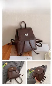 Detail of coffee brown leather backpack with elegant white butterfly charm and drawstring