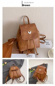 Detail of vintage brown leather backpack with silver butterfly charm and flap closure