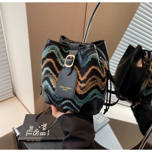 Detail view of woven knit bucket bag with wave patterns and black leather drawstring