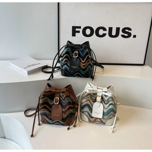 Three knit bucket bags with chevron pattern and leather trim on geometric steps