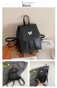 Detail view of black PU leather mini backpack featuring white butterfly hardware and drawstring