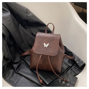 Detailed shot of dark brown vintage backpack with white butterfly buckle on leather jacket