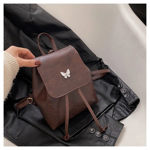 Close-up of vintage brown leather mini backpack with a white butterfly decorative clasp