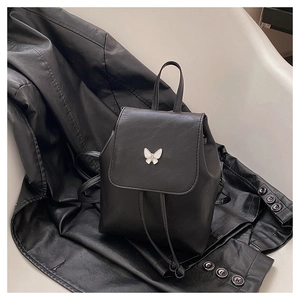 Detail of a black mini backpack with a white butterfly ornament and drawstring closure