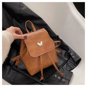 Detail of vintage brown mini backpack with silver butterfly buckle and leather texture