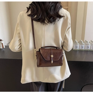 Détail du sac à bandoulière vintage marron foncé avec fermoir métallique et poignée