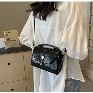Sac bandoulière en cuir noir vintage avec un élégant fermoir métallique semi-circulaire