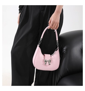 Detailed shot of pink half-moon shoulder bag with a silver metal bow clasp decoration