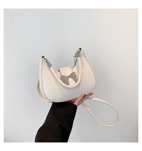 Close-up of white PU leather hobo bag with pearl-studded metal bow buckle detail
