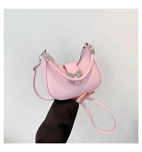 Detail of pink crescent handbag featuring a silver metallic bow buckle and leather texture