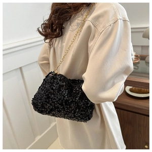 Detail of black sequined crossbody bag featuring a golden chain strap and sparkling texture