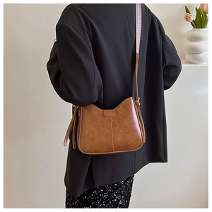 Sac bandoulière vintage marron avec large sangle à motifs ethniques porté par un modèle