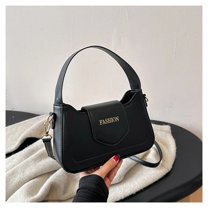 Détail d'un sac à main noir structuré avec lettrage Fashion doré sur une table ronde