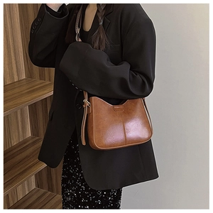 Détail d'un sac bandoulière vintage en cuir PU marron avec une large sangle réglable