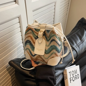 Bohemian knit bucket bag with wave patterns and white leather details on a leather sofa