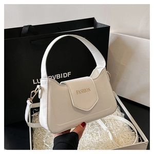 Détail d'un sac à main blanc en cuir avec lettrage doré dans une boîte cadeau