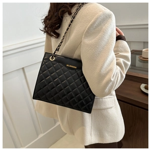 Détail du sac à bandoulière matelassé noir avec chaîne dorée et logo sur le cuir poli