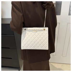 Détail du sac à bandoulière matelassé blanc porté par un mannequin en tenue chic