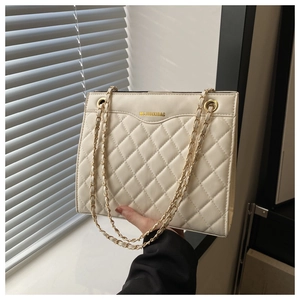Gros plan sur la texture en cuir matelassé blanc avec chaîne dorée et lettrage de marque