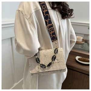 Détail du sac en paille bohème avec broderie florale et bandoulière à motifs