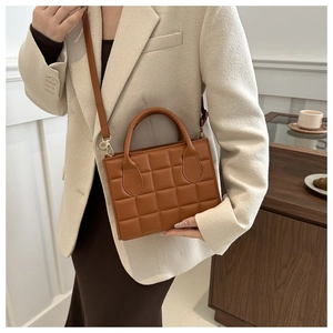 Detailed view of brown quilted PU leather handbag with detachable strap and golden hardware