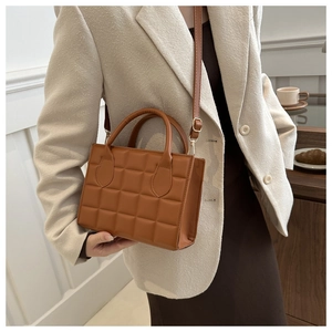 Brown quilted leather handbag worn by model against a stylish minimalist cafe background