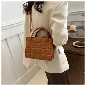 Lifestyle shot of a brown quilted handbag styled with a white blazer in a cafe setting