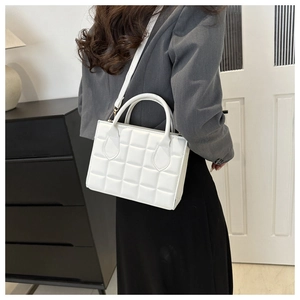 Model wearing a white quilted crossbody bag with a grey blazer and black skirt