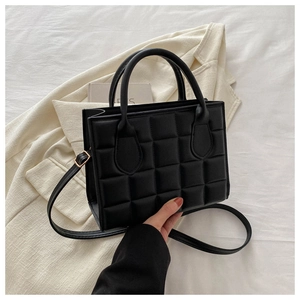 Detail of black quilted leather handbag with 3D waffle texture and top handle grip