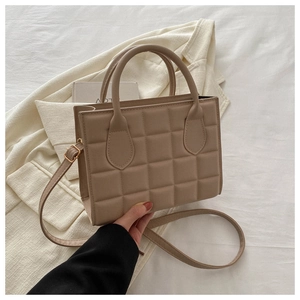 Detailed close-up of beige quilted square tote bag featuring elegant top handles and strap