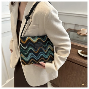 Detail of knit shoulder bag featuring colorful wavy stripes and a black leather logo tag