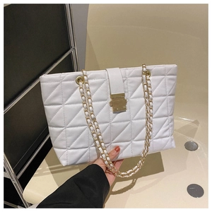 Close-up of white quilted tote bag with gold chain strap and square metal lock detail
