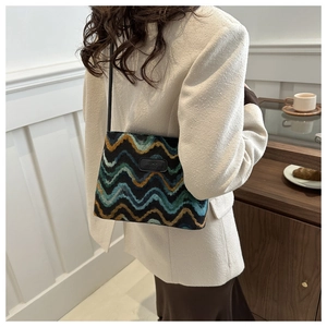 Detail of colorful wave texture on knitted underarm bag with leather logo patch