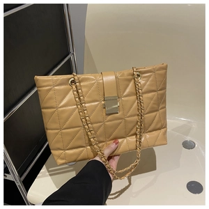 Detail of light brown quilted tote bag with gold chain strap and metal clasp closure