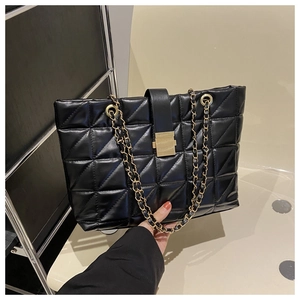 Detail of black quilted tote bag with golden metal buckle and leather chain strap