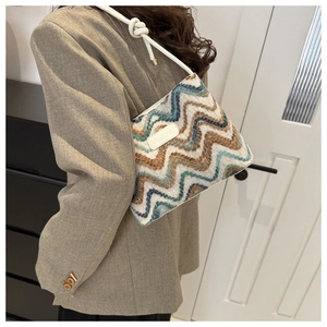 Close-up of zigzag knit hobo bag featuring knotted shoulder strap and brand leather patch