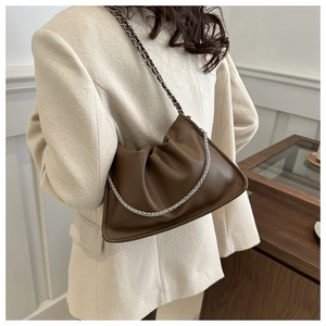 Detail of brown pleated soft leather shoulder bag with a metal chain strap on model