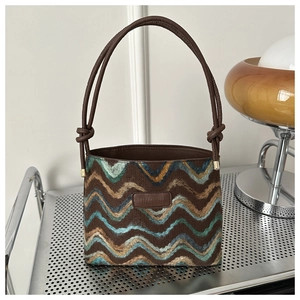 Detail of colorful wavy striped woven tote bag with a dark brown knotted leather handle