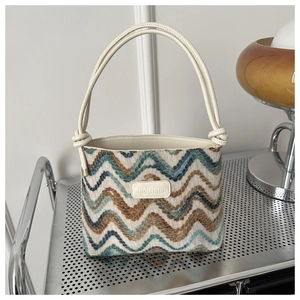 Close-up of zigzag knit shoulder bag featuring leather knotted handle and brand tag