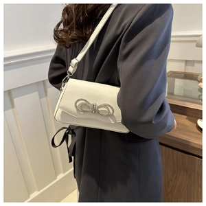 Détail du sac crème avec grand nœud en strass et bandoulière en cuir ajustable
