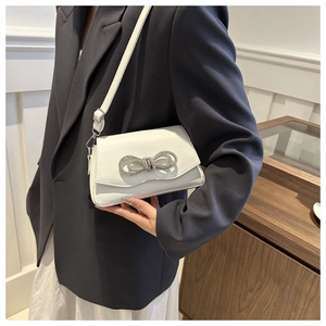 Détail d'un sac bandoulière blanc en cuir élégant orné d'un nœud en strass scintillant