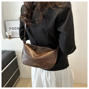 Detail of the brown crescent bag with retro leather texture and golden embossed logo