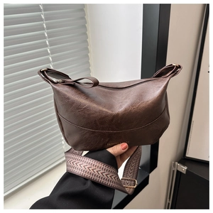 Close-up of vintage brown leather bag featuring textured PU finish and a woven shoulder strap