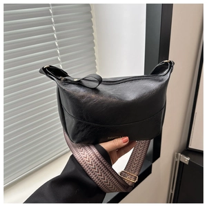 Detail of black soft leather crossbody bag with vintage woven shoulder strap and logo
